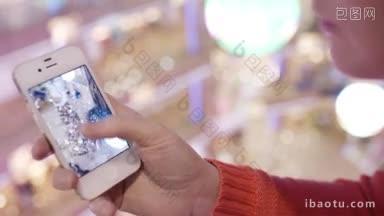 一名女子正在用她的智能手机查看圣诞树的照片，其中一张正在放大
